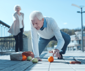 older man falling on ground with spilled grocery bag